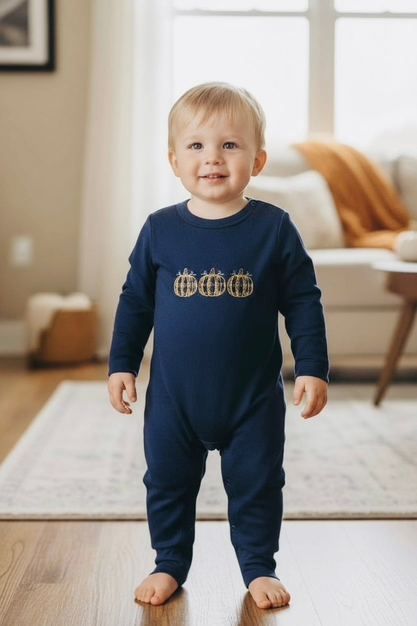Baby wearing navy onesie with pumpkins embroidered