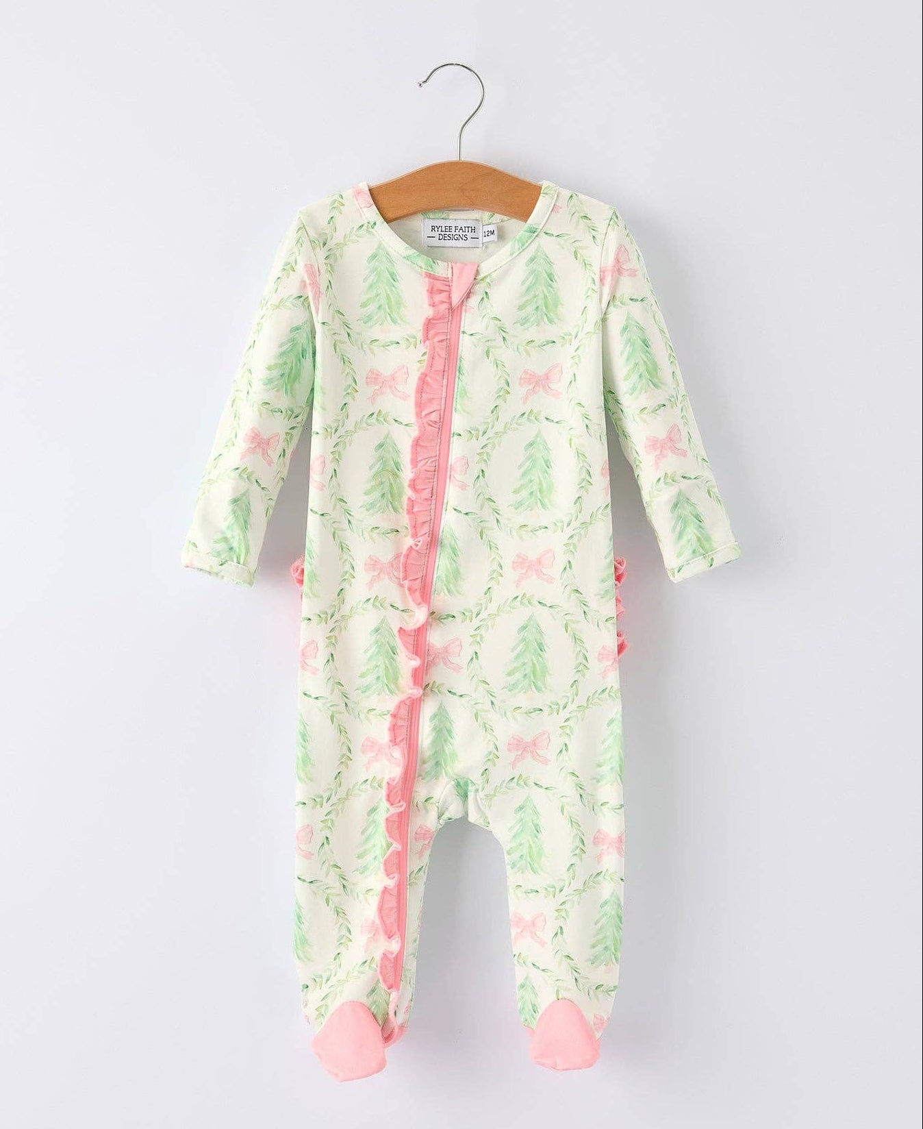 Baby onesie with pastel christmas pattern on a hanger against a white background