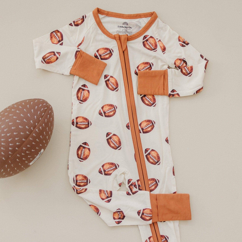 Baby onesie with football pattern and brown accents on a beige background