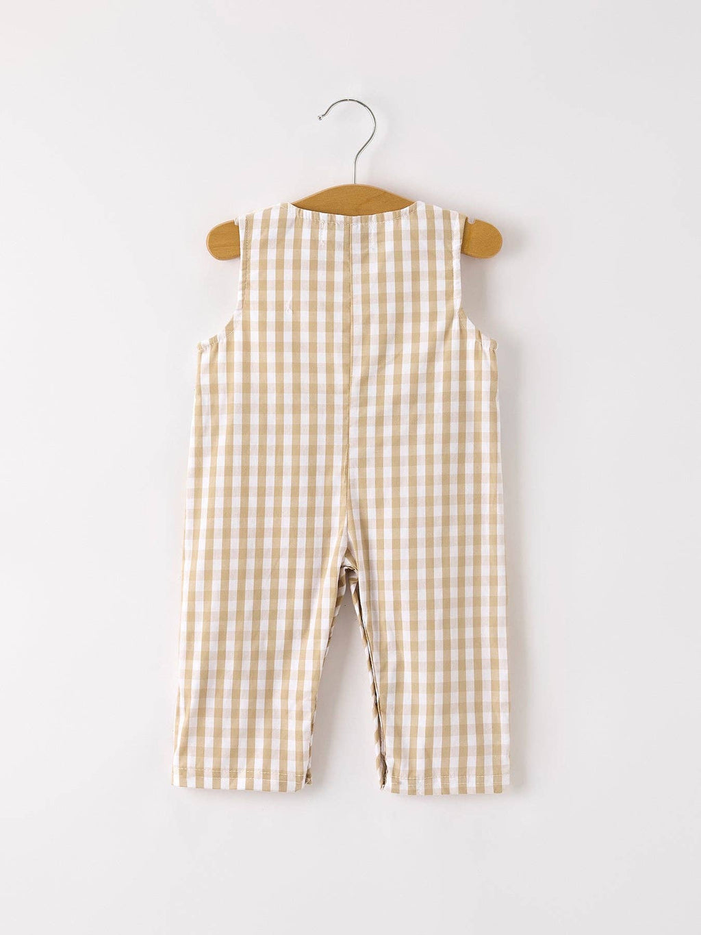 Checkered overalls on a wooden hanger against a white background