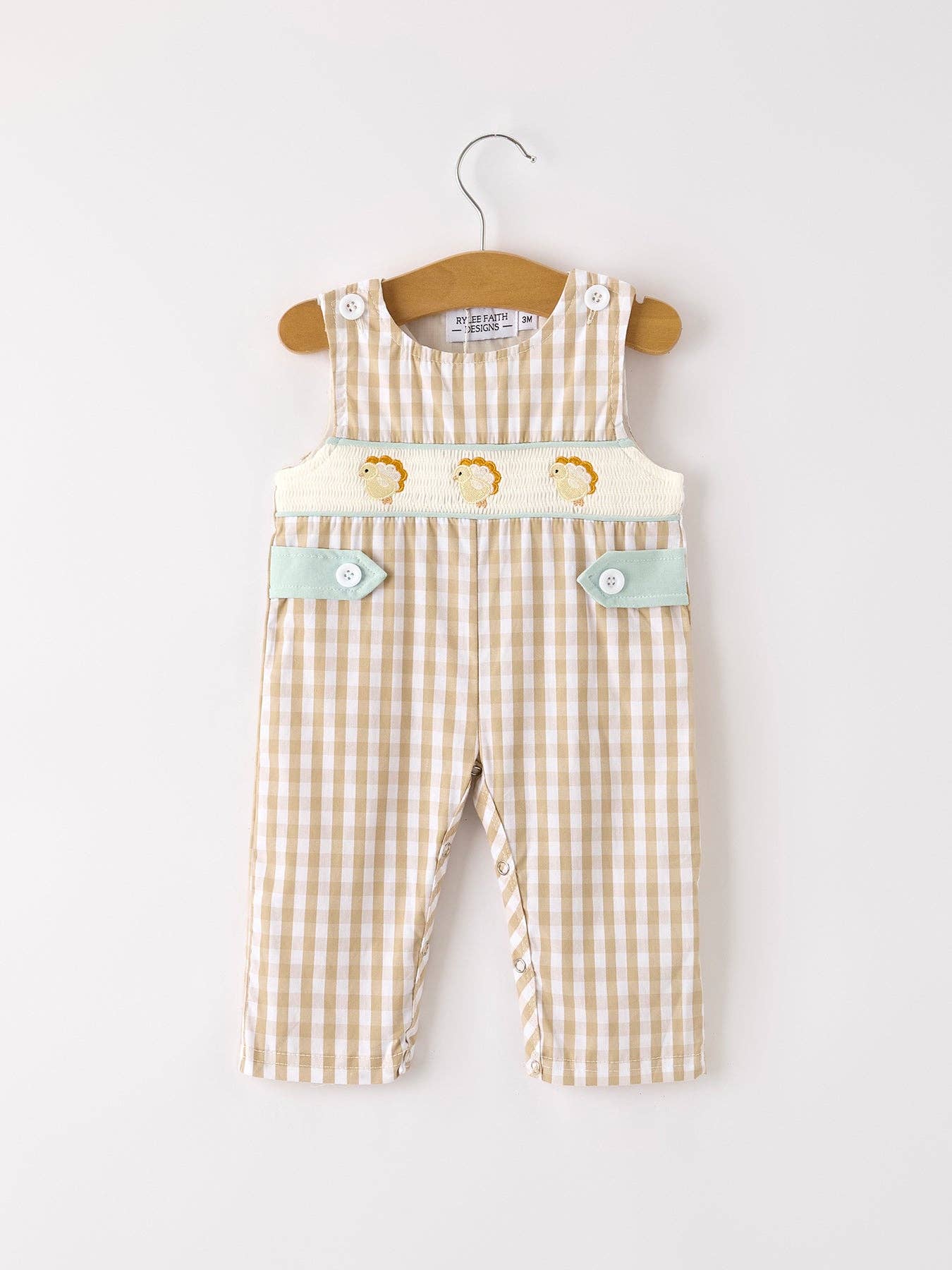 Baby overalls with turkey design on a hanger against a white background