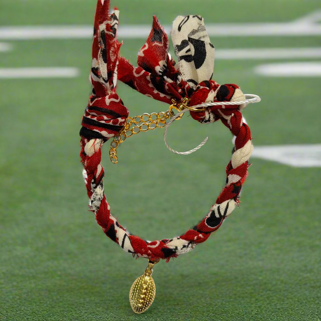 Bracelet with maroon, black, and white pattern and gold football charm on a white background