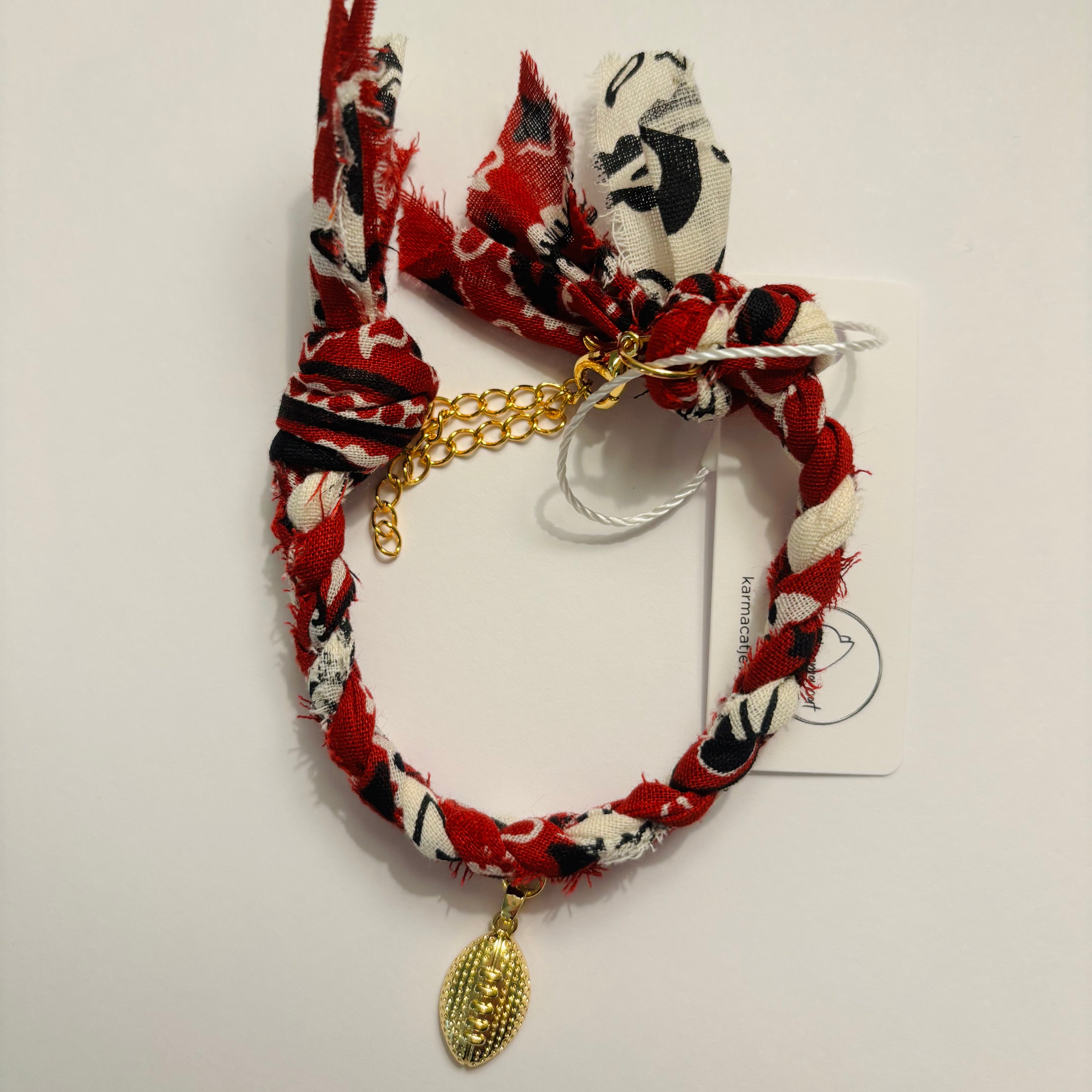 Bracelet with maroon, black, and white pattern and gold football charm on a white background