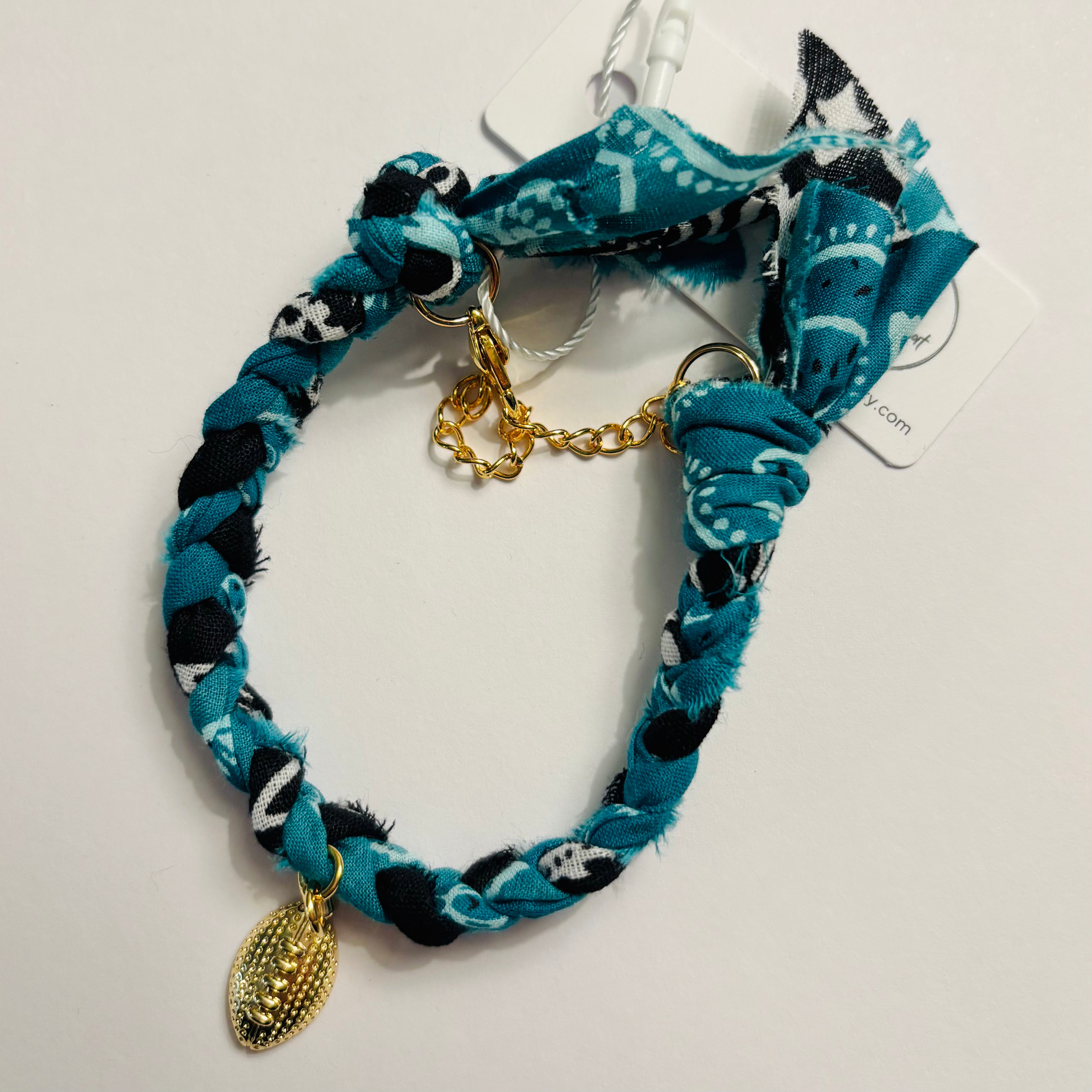 Bracelet with teal and black pattern and gold football charm on a white background