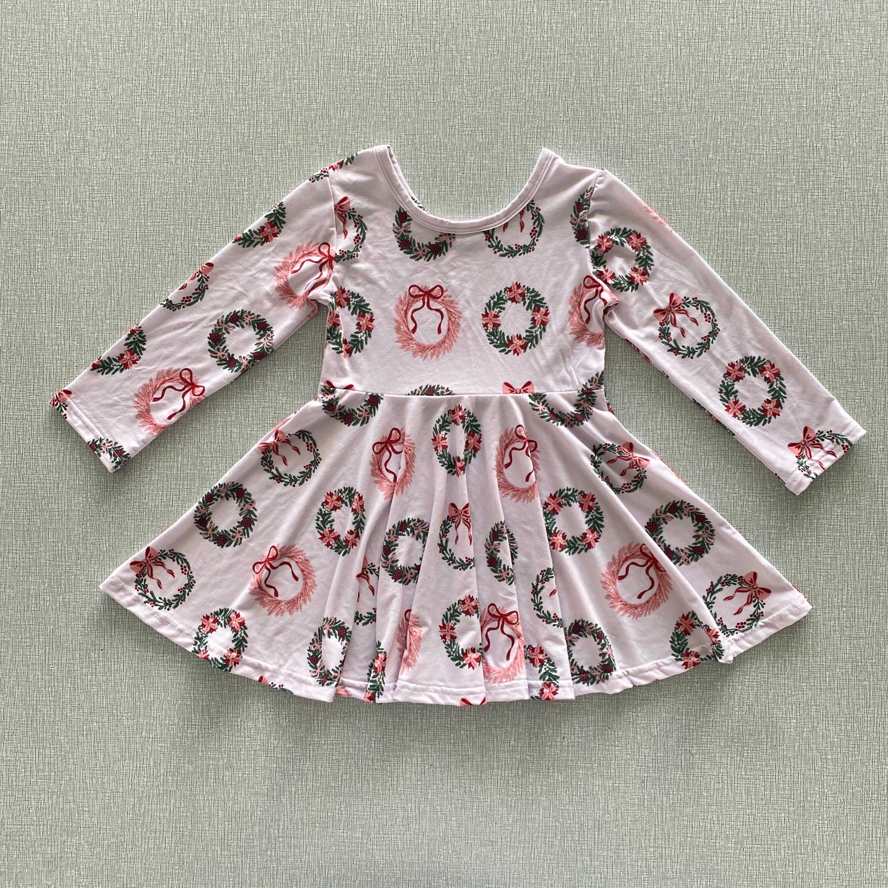 Pink dress with festive wreath and bow pattern on a light sand background