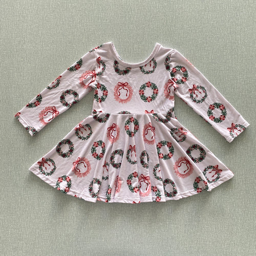 Pink dress with festive wreath and bow pattern on a light sand background