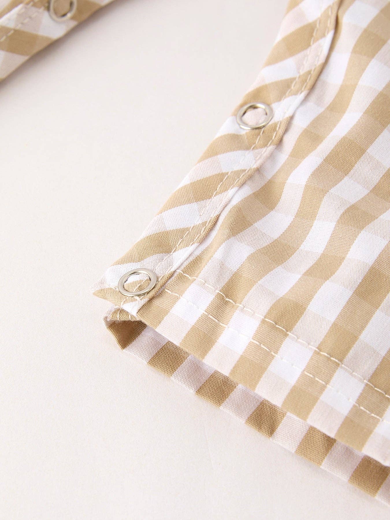 Close-up of a beige and white striped fabric with buttons on a light background