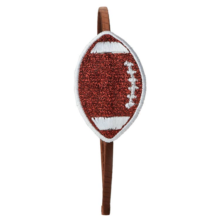 A football-shaped embroidered patch with a glittery brown body, white laces, and a white border, mounted on a brown wooden stick against a plain white background.