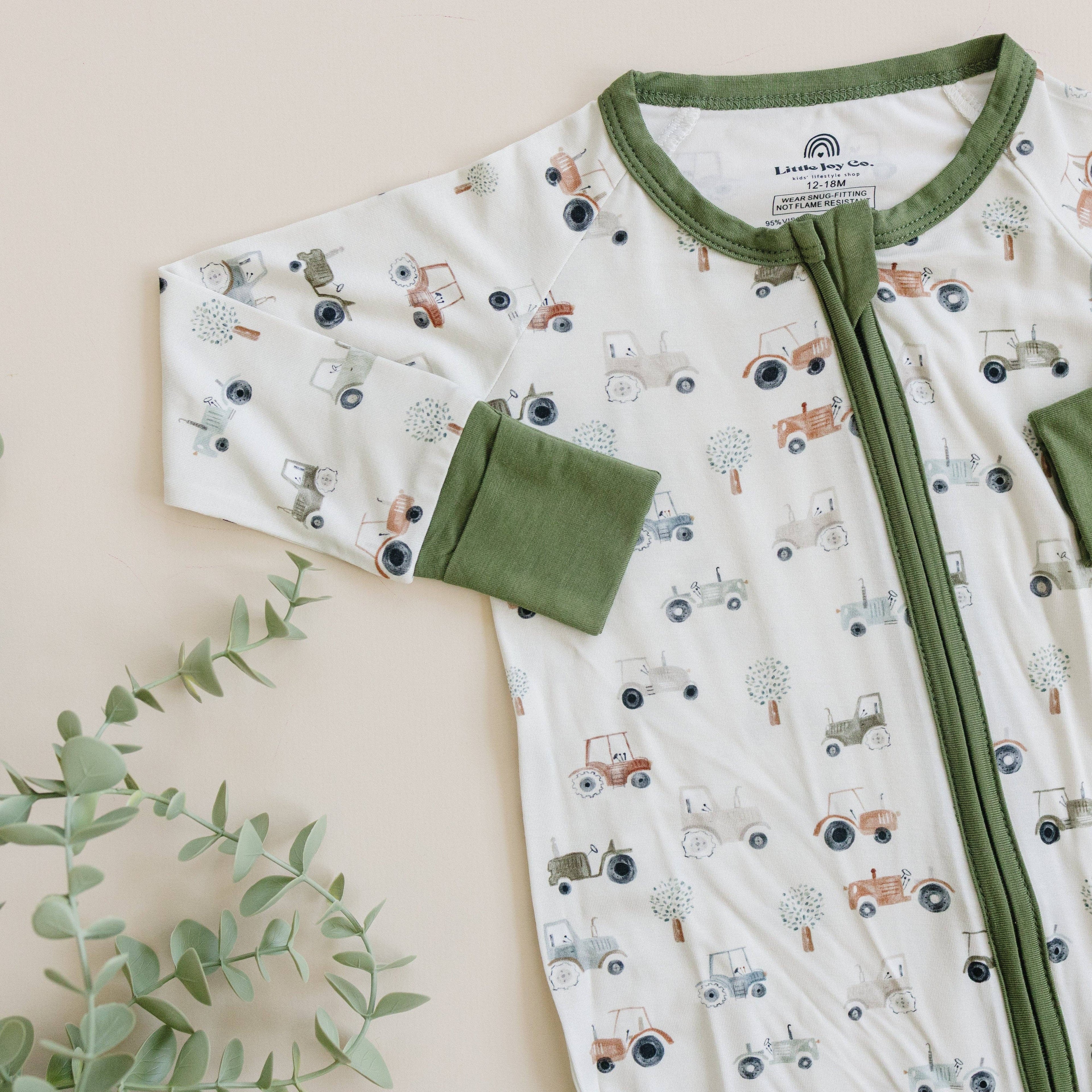 Baby outfit with green trim and tractor pattern on a beige background