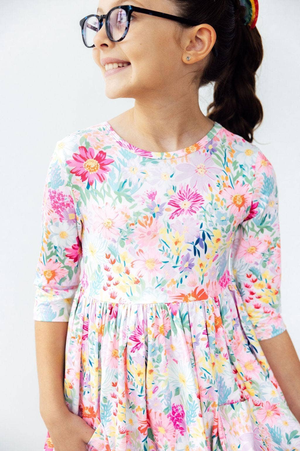 Child wearing a colorful floral dress against a white background